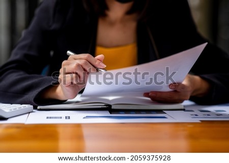 A Businesswoman hand using a calculator with documents financial statistic stock photo,discussion and analysis data the charts and graphs.Market research reports Accounting Finance concept
