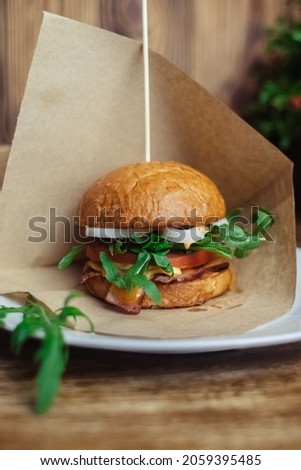 Close-up of a standard burger. Adult fast food in a restaurant or cafe. Macro photo of burger ingredients with meat, cheese and herbs. Eco burgers for the whole family