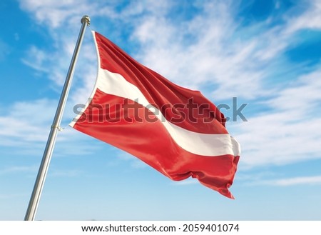  flag of Latvia waving against the backdrop of a blue sky