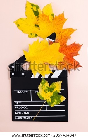 Clapperboard and seasonal autumn maple leaves. Movie clapper board on an autumn background. Top view.
