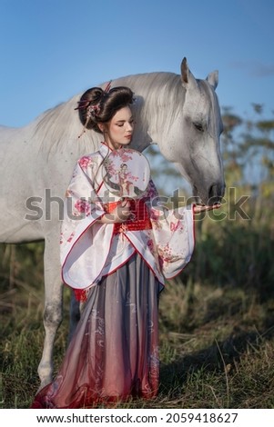 Girl in kimono with white free horse in the field