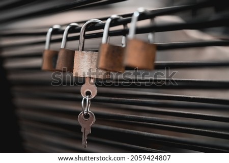 A closeup shot of padlocks with keys hanging on a blurred background