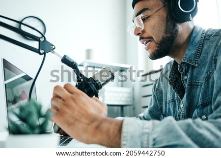 Mixed race content creator streaming his audio show at home studio using professional microphone and laptop