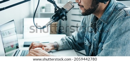Mixed race content creator broadcasting his audio show at cozy home studio using professional microphone and laptop
