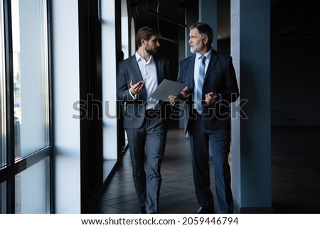 Two colleagues communicating in corridor, partners walking in the modern office Royalty-Free Stock Photo #2059446794