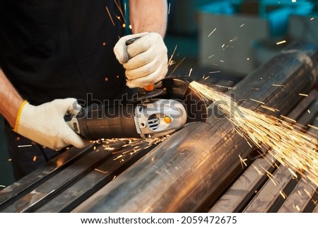 angle grinder for cutting metal, stones and ceramics. male hands in gloves cut a piece of iron pipe with sparks with a typewriter Royalty-Free Stock Photo #2059472675