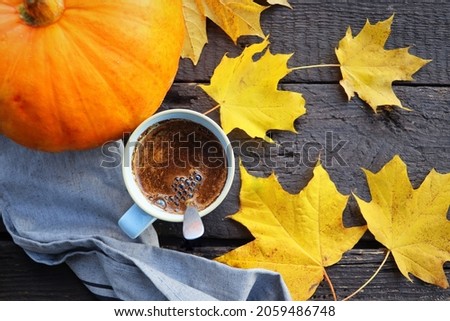 Autumn background. Blurred autumn leaves and pumpkin background with hot cup of coffee .