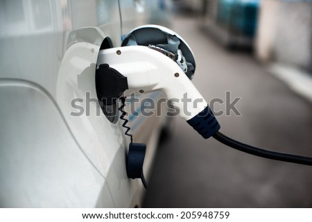 Charging an electric car with the power cable supply plugged in. Royalty-Free Stock Photo #205948759
