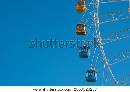 Close view of a ferris wheel, under blue sky.