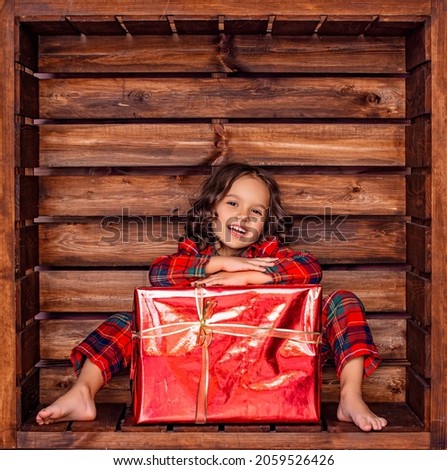 Beautiful cute girl child in a wooden square location in Christmas decorations