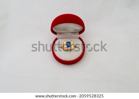 Luxury gold ring in a red container isolated on white background. Top view of woman accessory jewel in a open box. 