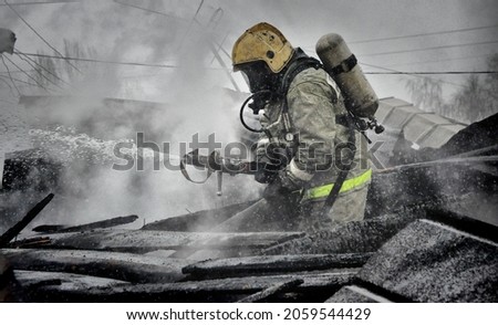 Firefighters with the inscription on the back in Russian " fire protection. Emercom of Russia" extinguish a fire on the roof of a house on a frosty winter day Royalty-Free Stock Photo #2059544429