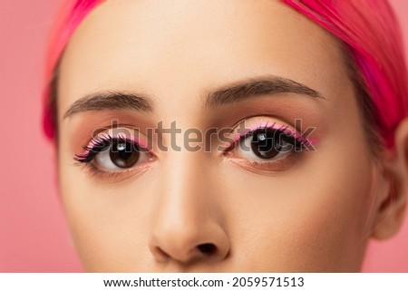 close up of cropped young woman with colorful hair looking at camera isolated on pink