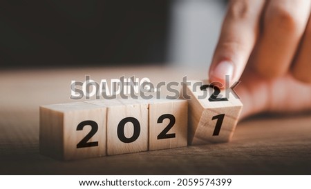 Start change year loading 2021 to 2022 , Businessman flipping wooden cube block to change 2021 year to 2022 year. Beginning new year for planning success. background for happy new years concept. Royalty-Free Stock Photo #2059574399