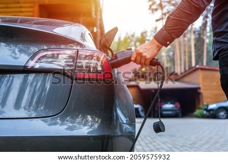 Electric car charging with station, EV fuel advance and modern eco system, Save the earth conception. man connecting a charging cable to a car from an electric car charging station. Royalty-Free Stock Photo #2059575932