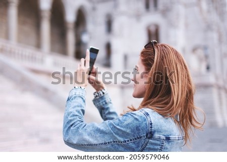 Young redhead tourist woman photographing the monuments in city, famous place, travel