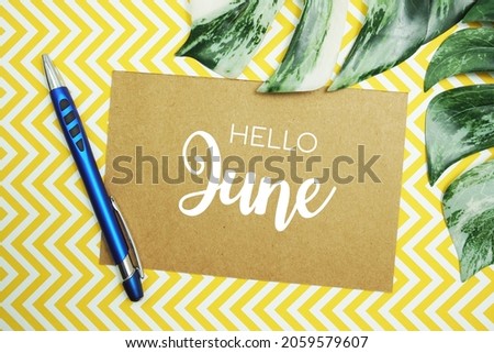 Hello June typography text on paper card with Monstera leaves