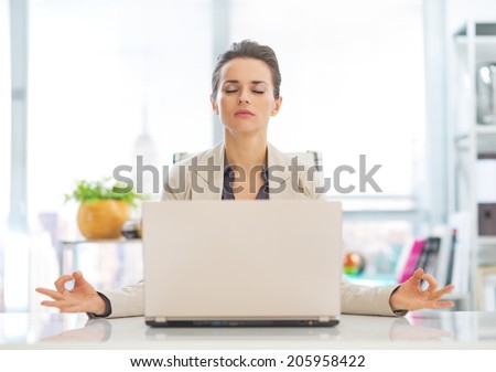 Business woman meditating near laptop Royalty-Free Stock Photo #205958422