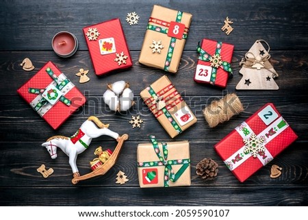 Handmade wrapped red, green gift boxes decorated with ribbons, snowflakes and numbers, Christmas decorations and decor on wooden table Xmas advent calendar concept Top view Flat lay Holiday card