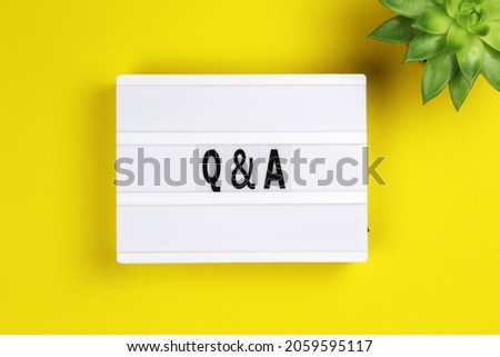 question and answer word on lightbox with succulent flower on yellow background, flat lay