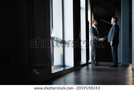 Full length view of businessmen shaking hands in office building Royalty-Free Stock Photo #2059598243