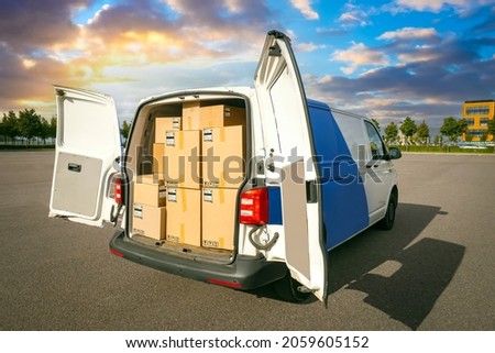 Van with cardboard boxes. Delivery service van back view. Courier van with open rear doors. Courier service car. Minivan for move. Boxes for moving in truck. Concept - renting minivan for moving. Royalty-Free Stock Photo #2059605152