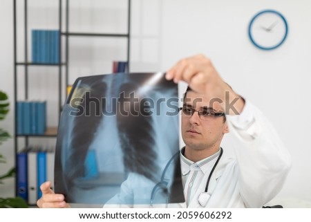 In a hospital office, a pulmonology physician checks a patient's lung x-ray. Royalty-Free Stock Photo #2059606292