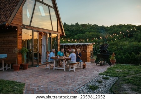 Three generation family having a garden party in the summer. They are sitting at the dining table in the backyard and having dinner Royalty-Free Stock Photo #2059612052