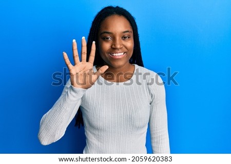 African american woman with braided hair wearing casual white sweater showing and pointing up with fingers number five while smiling confident and happy. 