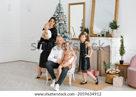 A stylish beautiful large family celebrates Christmas and New Year in the living room in their house near the Christmas tree