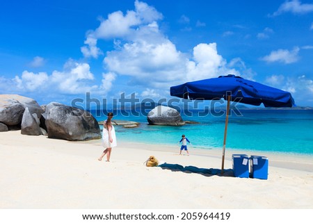 Picture perfect beach with blue umbrella, white sand, turquoise ocean water and blue sky at tropical island in Caribbean