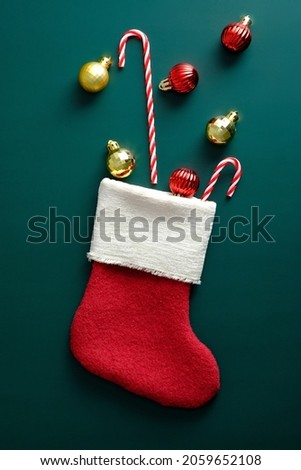Christmas stocking with decorations and candy canes on dark green background.