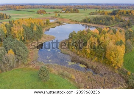 Aerial landscape of dark lake and colorful yellow and green autumn forest