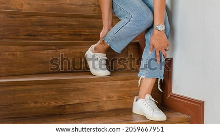 Woman loses control and cannot walk on stairs, she stops and hold her legs for support and rest with feel tingling. Concept of Guillain barre syndrome and numb legs disease or vaccine side effect. Royalty-Free Stock Photo #2059667951