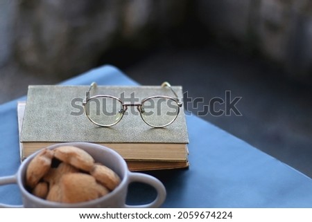 Bowl of cinnamon cookies, hardcover books and reaing glasses. Selective focus.