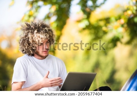 A student with an afro hairstyle sitting in nature and uses a laptop during a corona virus pandemic. High quality photo