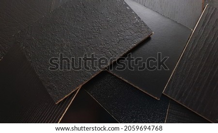 close up view showing multi surface of melamine samples contains wooden, stone, leather, matt, peel, peal textures in black color for selection. furniture particle board structure samples. 