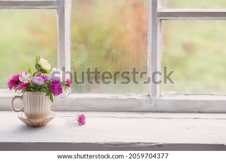 flowers in little cup on old white windowsill Royalty-Free Stock Photo #2059704377