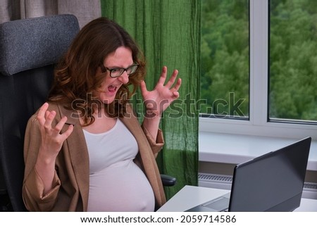 Pregnant woman with laptop in home office gets angry by raising her hands