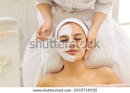 Top view of cosmetologist do facial mask for healthy glowing skin for smiling female client. Dermatologist make beauty procedures for woman patient in aesthetic medical clinic. Cosmetology concept. Royalty-Free Stock Photo #2059718930