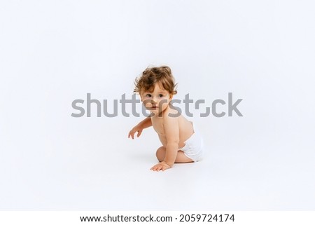 Beautiful child. Portrait of little cute toddler boy, baby in diaper curiously looking away isolated over white studio background. Concept of childhood, motherhood, life, birth. Copy space for ad Royalty-Free Stock Photo #2059724174