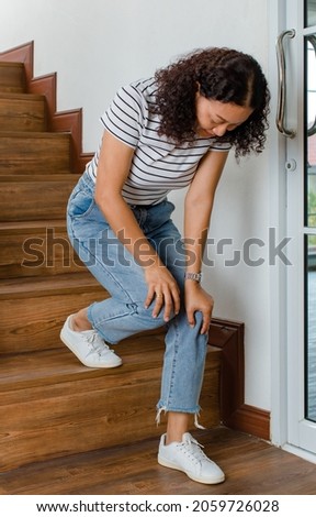 Woman loses control and cannot walk on stairs, she stops and hold her knees for support and rest with feel tingling. Concept of Guillain barre syndrome and numb legs disease or vaccine side effect. Royalty-Free Stock Photo #2059726028