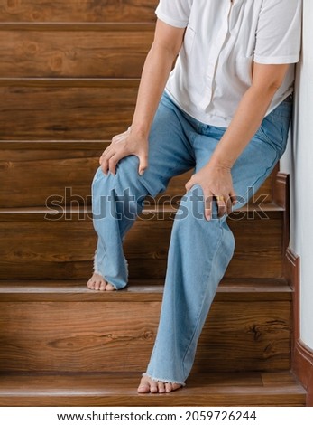 Woman stops for rest and leaning on wall for support while she cannot climb stairs with tingling legs. Concept of Guillain barre syndrome and numb legs disease or vaccine side effect.