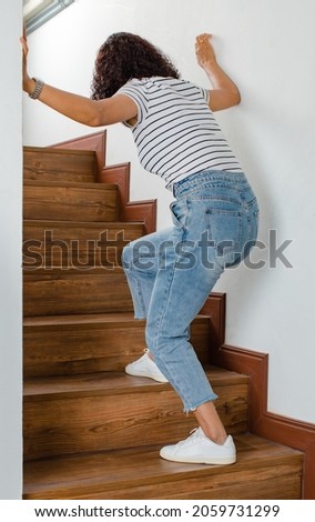 Woman lose control and cannot walk on stairs, she stops and use hand hold wall for support with feeling and tingling. Concept of Guillain barre syndrome and numb hands disease effect. Royalty-Free Stock Photo #2059731299