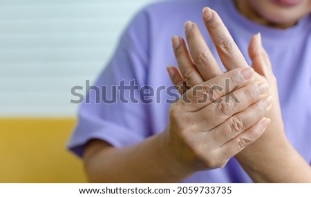 Woman using hand to hold other her palm with feeling pain, hurt and tingling. Concept of Guillain barre syndrome and numb hands disease.