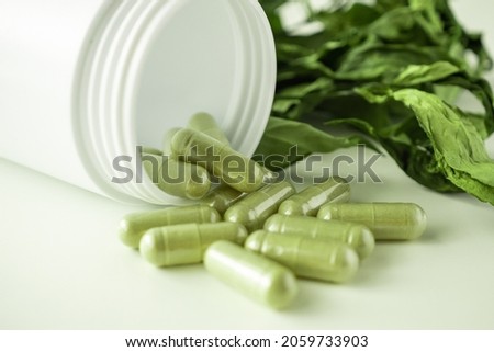 Herbal medicine capsules with Andrographis paniculata leaf on white background