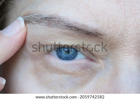 middle aged female's eye with drooping eyelid. Ptosis is a drooping of the upper eyelid, lazy eye. Cosmetology and facial concept, first wrinkles, closeup Royalty-Free Stock Photo #2059742582