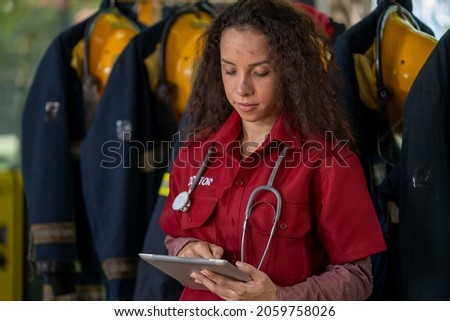 Portrait of confident female firefighter in medical uniform standing at fire station.