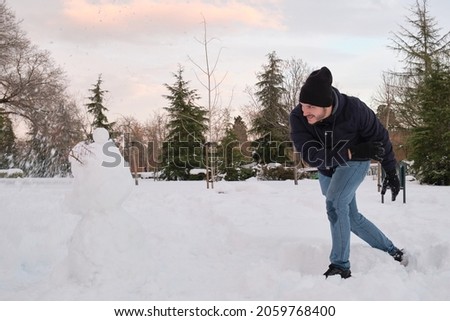Young caucasian man destroying a snowman