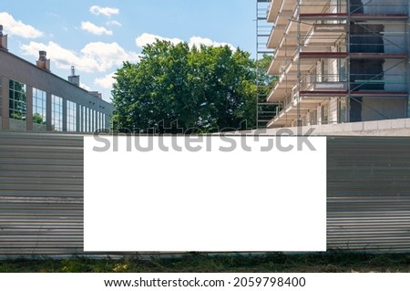 Blank white banner for advertisement on the fence of construciton site amog trees